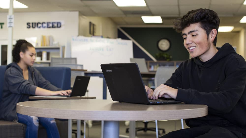 two students working on laptops